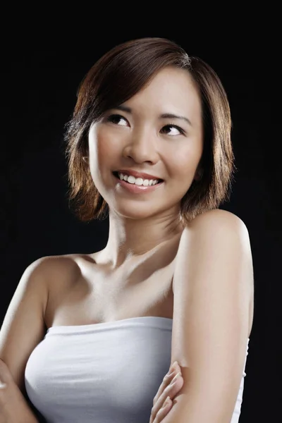 Woman in white tube top smiling with arms folded