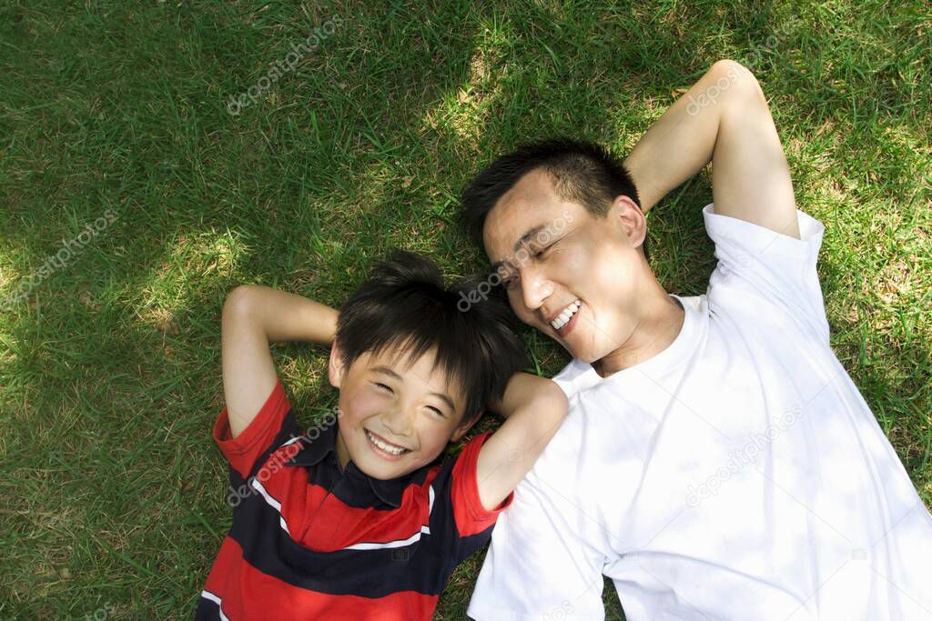 Father and son lying on the grass