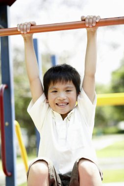Çocuk oyun parkında parmaklıklarda asılı duruyor.