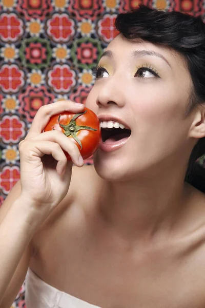 Woman about to eat tomato