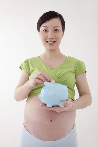 Schwangere Steckt Münze Sparschwein — Stockfoto