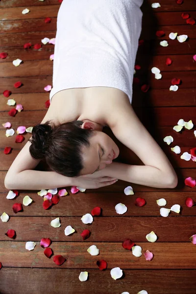 Woman Towel Lying Forward Wooden Platform Flower Petals Scattered Everywhere — Stock Photo, Image