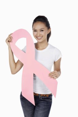 Elinde pembe meme kanseri kurdelesiyle gülümseyen bir kadın.