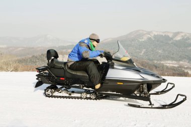 Genç adam kar motosikletine biniyor