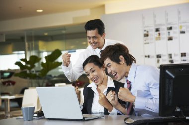 İş adamları masadaki dizüstü bilgisayara bakarken tezahürat yapıyorlar