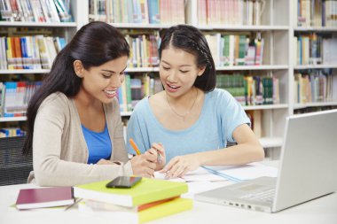 İki öğrenci kütüphanede birlikte okuyorlar.