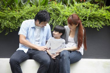 Aile dışarıda birlikte oturuyor.