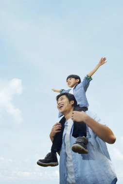 Baba oğlunu omuzlarında taşıyor.