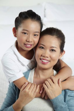 Kız annesine arkadan sarılıyor.