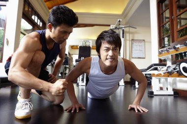 Kişisel antrenör erkeğin çalışmasına yardım ediyor.