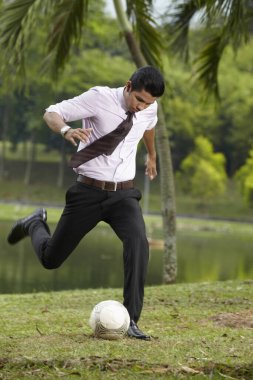 Genç işadamı futbol topunu tekmeliyor