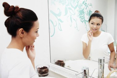 Bir kadın aynada yüzünü kontrol ediyor.