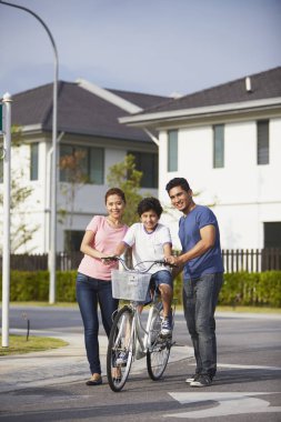 Ebeveynler oğluna bisiklet sürmeyi öğretiyor.