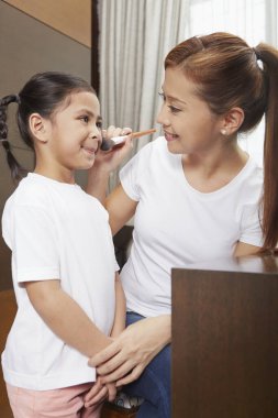 Mutlu anne kızı için makyaj yapıyor.