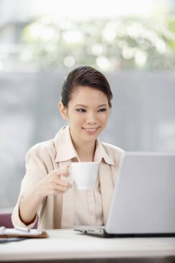 İş kadını içki içerken dizüstü bilgisayarda çalışıyor