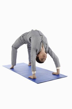Yetişkin bir iş kadını yoga pozisyonunda geriye doğru eğiliyor.
