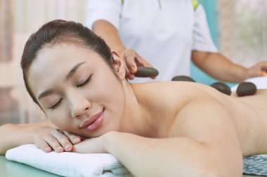 Genç bir kadının sırtına masaj taşı.