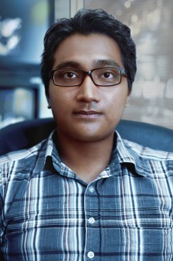 Adam oturuyor ve kameraya bakıyor.