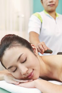 Genç bir kadının sırtına masaj taşı.