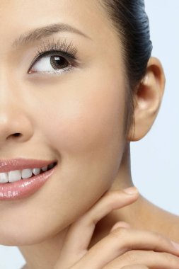 Kadın yüzüne dokunuyor ve gülümsüyor.