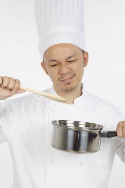 Asyalı şef tencereyle yemek yapıyor, hayal kırıklığına uğramış görünüyor.