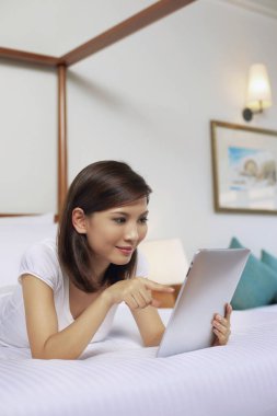 yatakta dijital tablet kullanan kadın