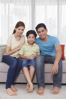 Üç kişilik aile kameraya gülümsüyor.