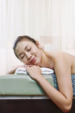 Genç bir kadın uzanmış, dinleniyor.