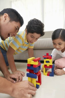 Neşeli baba çocuklarıyla oynuyor.