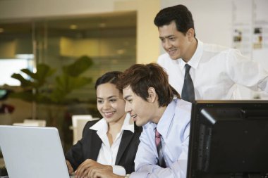 İş kadını, meslektaşları izlerken laptop kullanıyor.