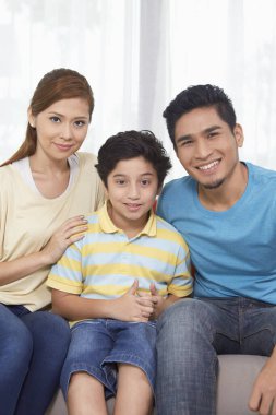 Üç kişilik aile kameraya gülümsüyor.