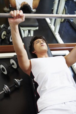 Adam spor salonunda ağırlık kaldırıyor.