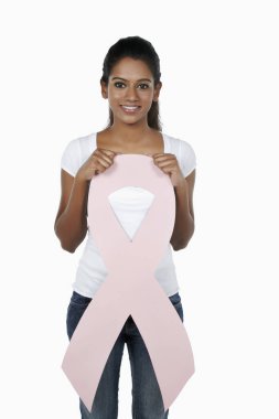 Elinde pembe meme kanseri kurdelesiyle gülümseyen bir kadın.