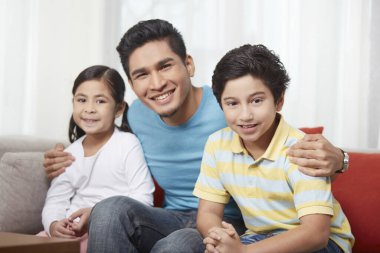 Baba ve çocuklar kameraya gülümsüyor.