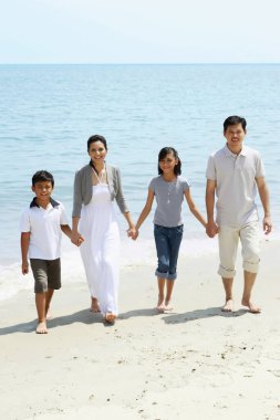 Aile sahilde yürürken el ele tutuşur.