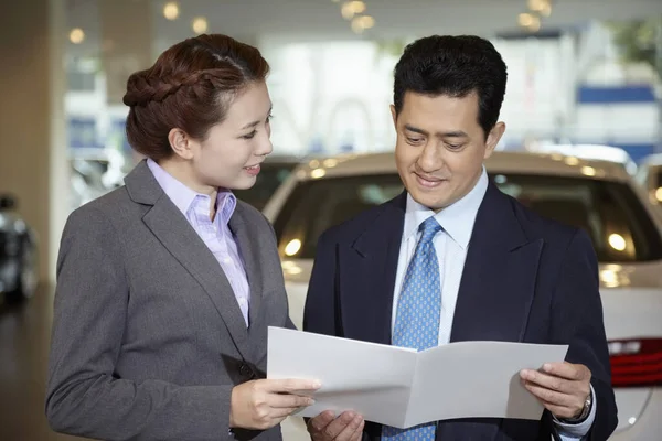 销售代表向顾客解释汽车规格手册 — 图库照片