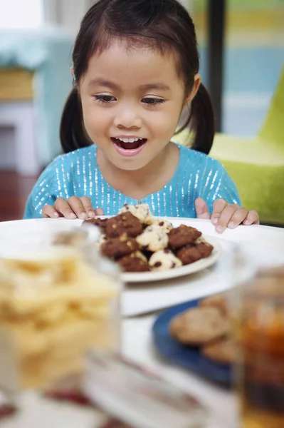 女の子は笑顔ながら クッキーのプレートを見て — ストック写真