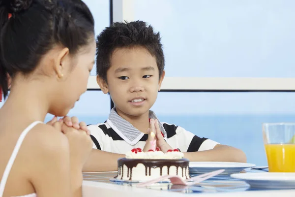 Girl making a birthday wish, boy looking at her