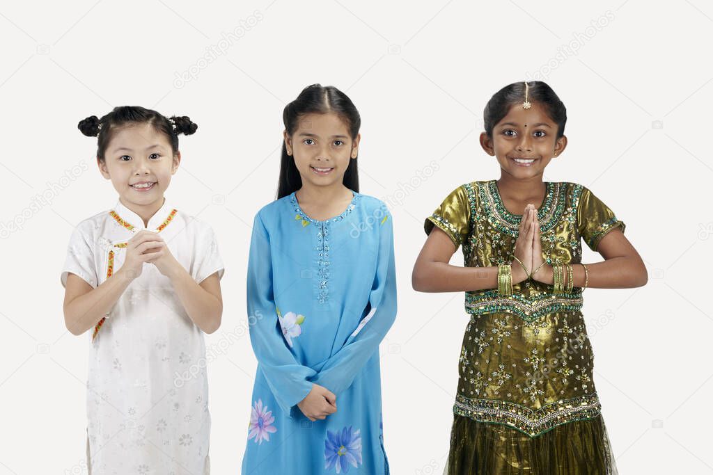 Girls in traditional clothing smiling with greeting hand gestures