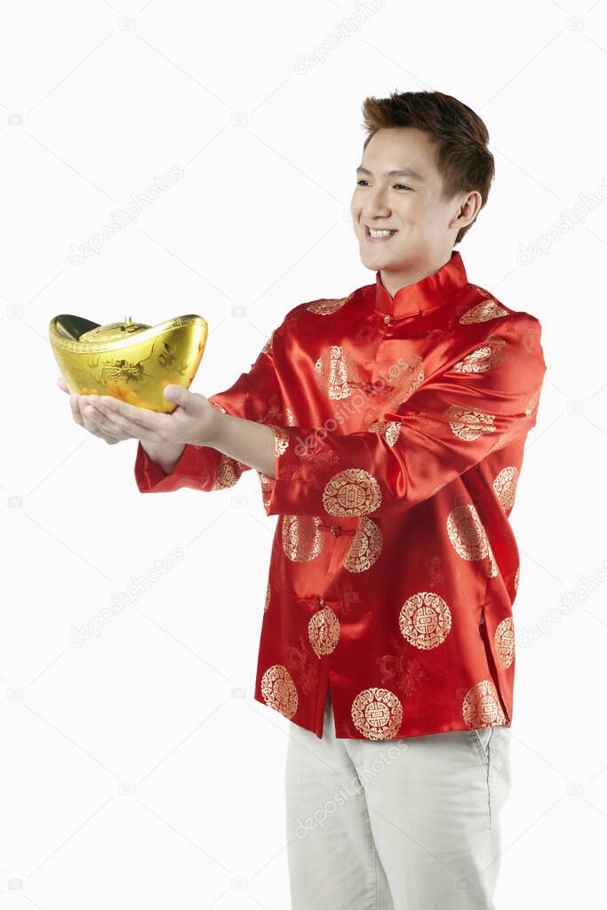 Man in traditional clothing offering a gold ingot