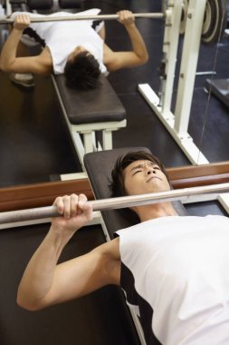 Adam spor salonunda ağırlık kaldırıyor.