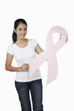 Elinde pembe meme kanseri kurdelesiyle gülümseyen bir kadın.