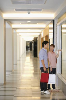 Kadın ve erkek vitrinin önünde dikiliyor.