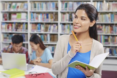 Kütüphanedeki öğrenciler not defteri tutuyorlar.