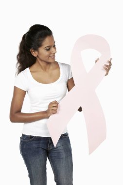 Elinde pembe meme kanseri kurdelesiyle gülümseyen bir kadın.