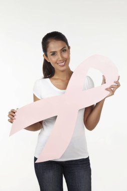Elinde pembe meme kanseri kurdelesiyle gülümseyen bir kadın.