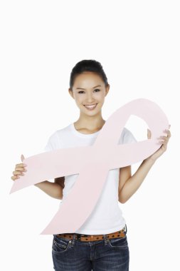 Elinde pembe meme kanseri kurdelesiyle gülümseyen bir kadın.