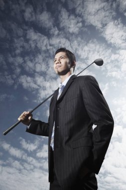 Golf sopası tutan genç bir iş adamı.