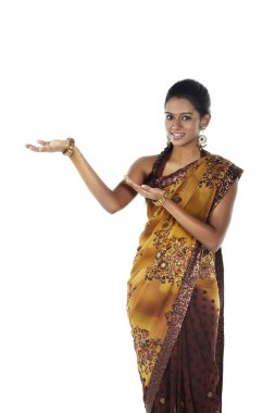 Sari giymiş bir kadın el hareketleriyle gülümsüyor.