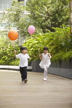 Kız ve erkek balon tutarken koşuyorlar.